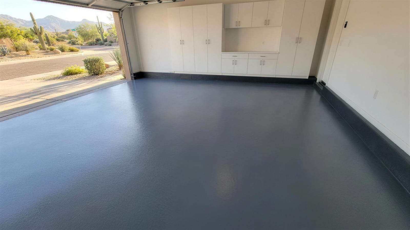 Solid dark gray polyaspartic garage floor with a satin finish, door open to a desert landscape
