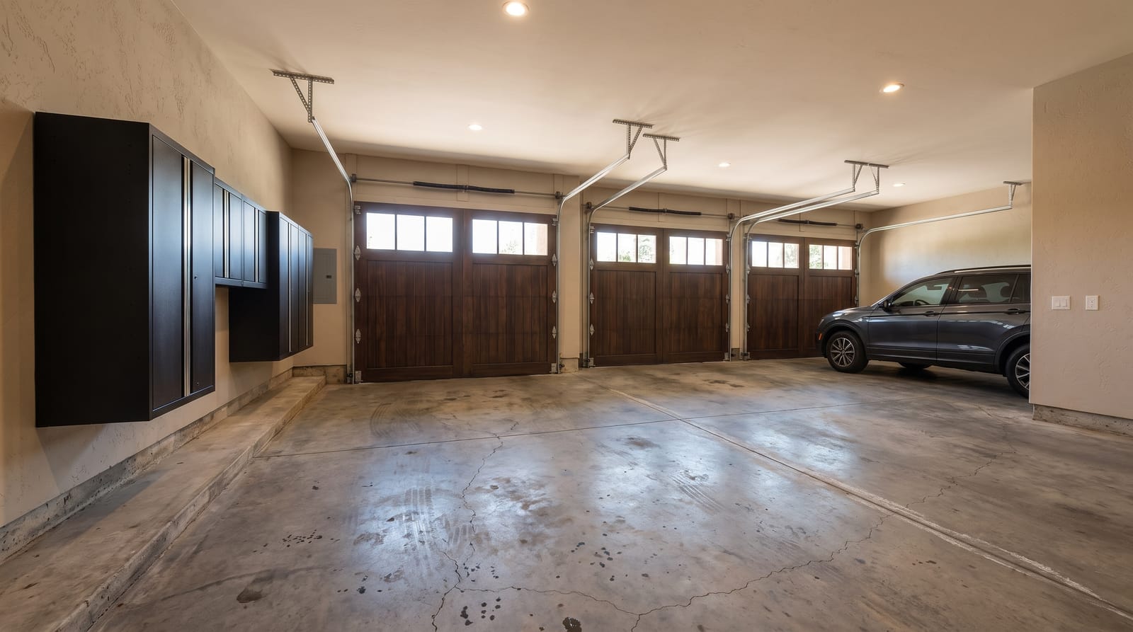 The same three-car garage with bare, stained concrete before coating